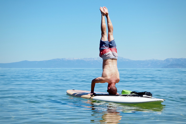 A man performing a head stand on the Dax DownDog stand up paddle board on Lake Tahoe