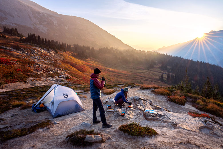 A Nemo tent set up at camp with the sun setting on the horizon
