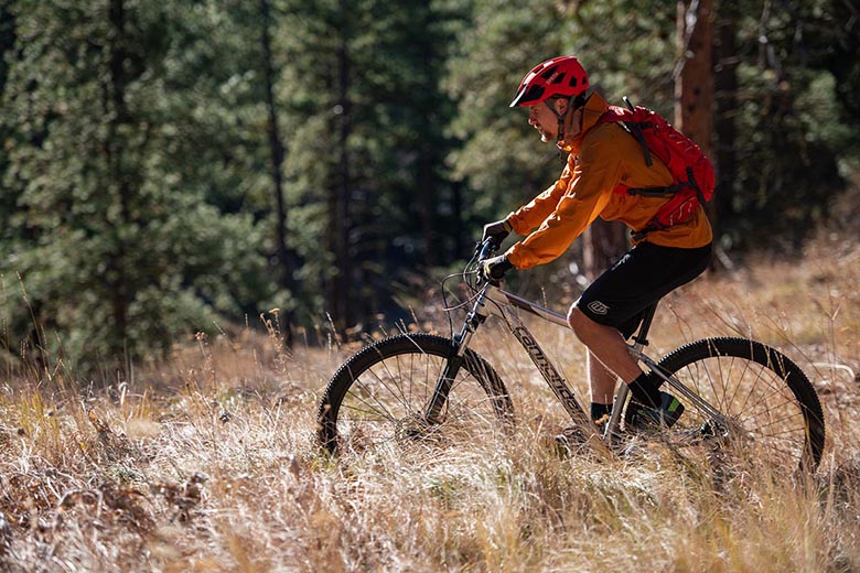 A man rides a mountain bike across a golden mountain field. 