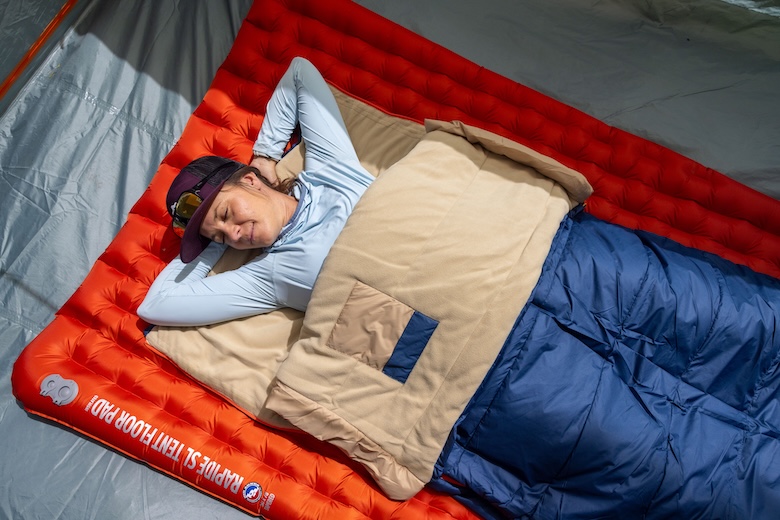 A woman lounges on her back in a tent in the Wawona Bed 20 sleeping bag