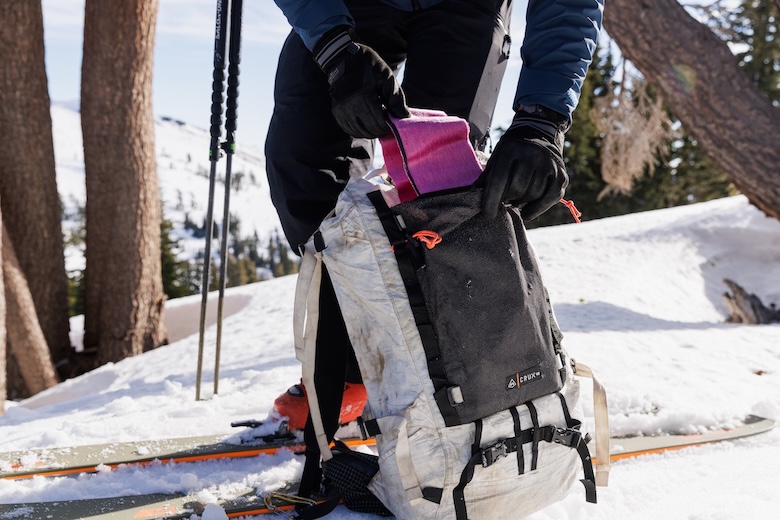 Loading skins into the front pocket of the HMG Crux 40 backpack