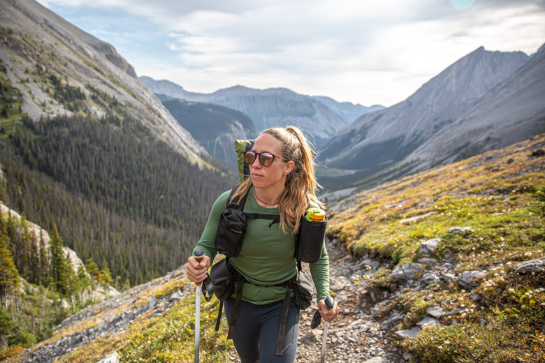 A woman hiking  in the mountains in a green baselayer
