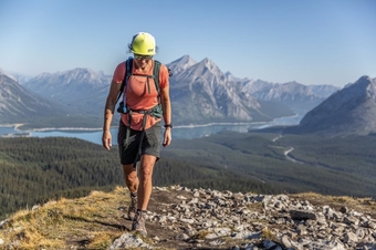A woman walks along the ridgeline in a mountain range wearing a pair of REI Sahara Convertible pants