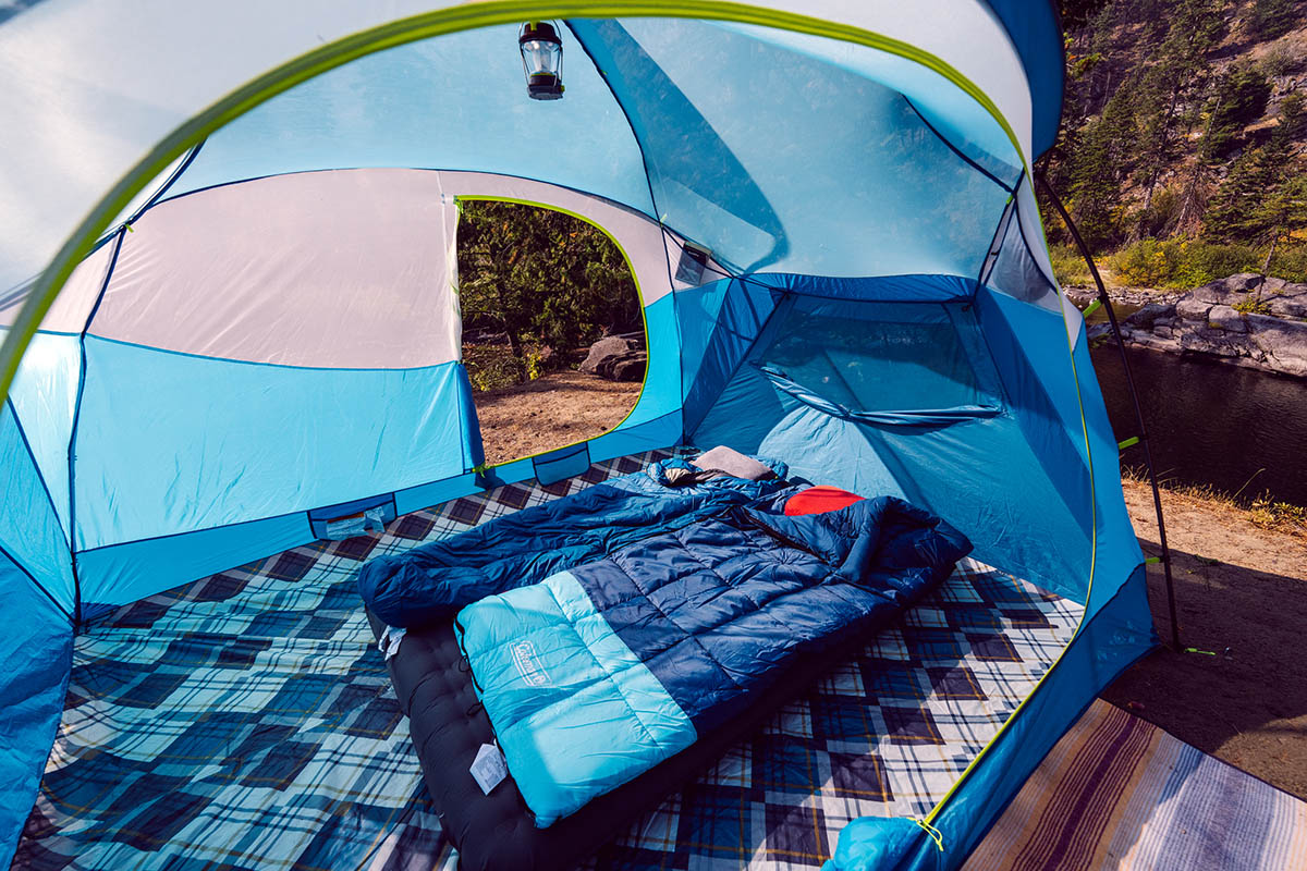 The interior of a bright blue car camping tent with a wide comfortable mattress and sleeping bags.