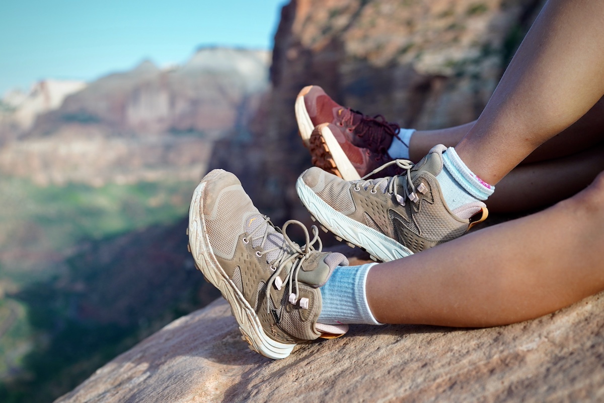 A pair of hikers take a break on a rock in the sunny afternoon.