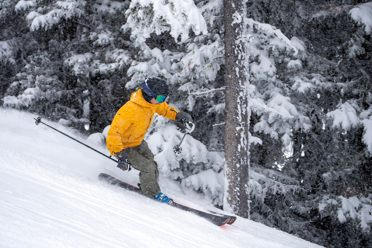 A man skiing quickly downhill in a yellow ski jacket