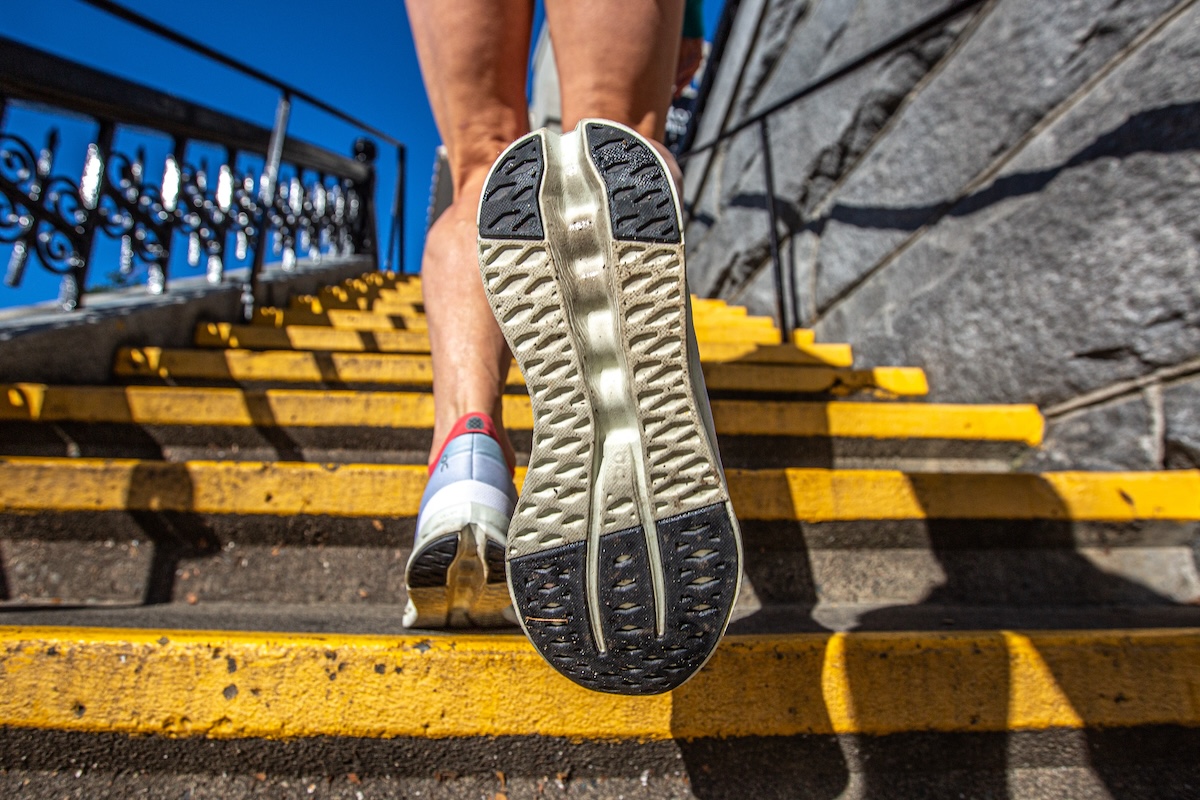 A runner's feet are shown climbing stairs to view the outsole traction of ON shoes