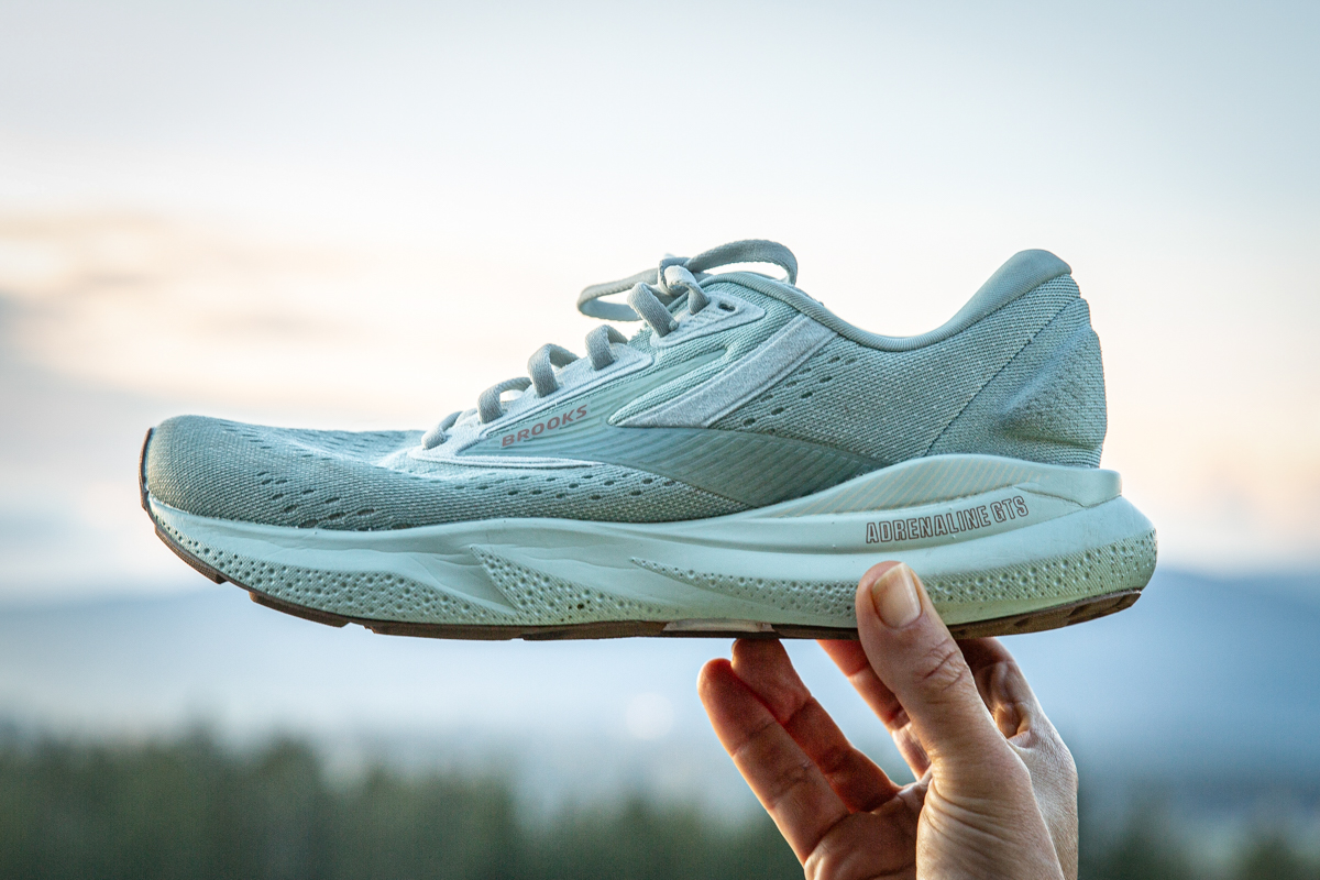 The midsole of the Brooks Adrenaline shoe is held up to show its thickness 