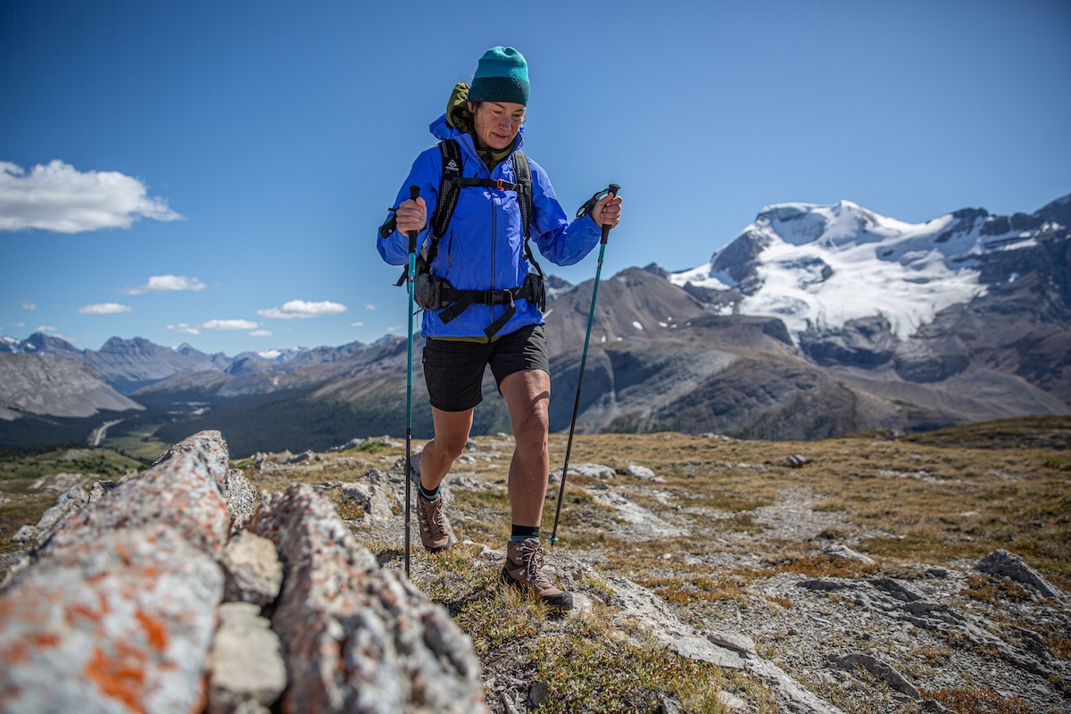 A woman hikes down a trail in a hardshell jacket