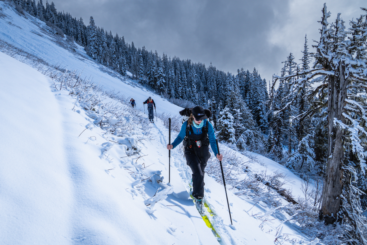 A group of skiiers tour through the forest wearing breathable midlayers. 