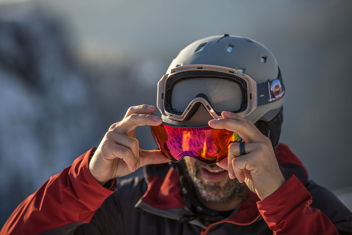 A close-up of a man changing the lens on his goggles
