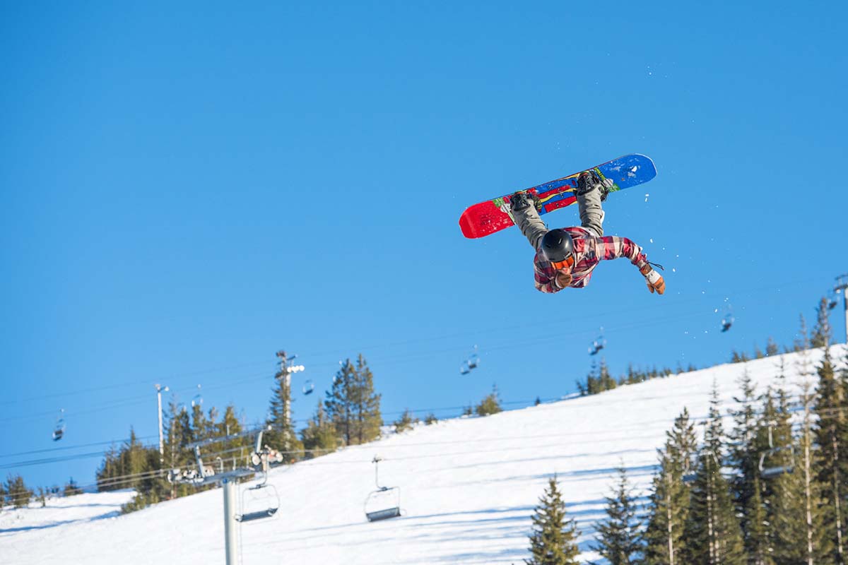 A snowboarder doing a backflip in the snowboard park