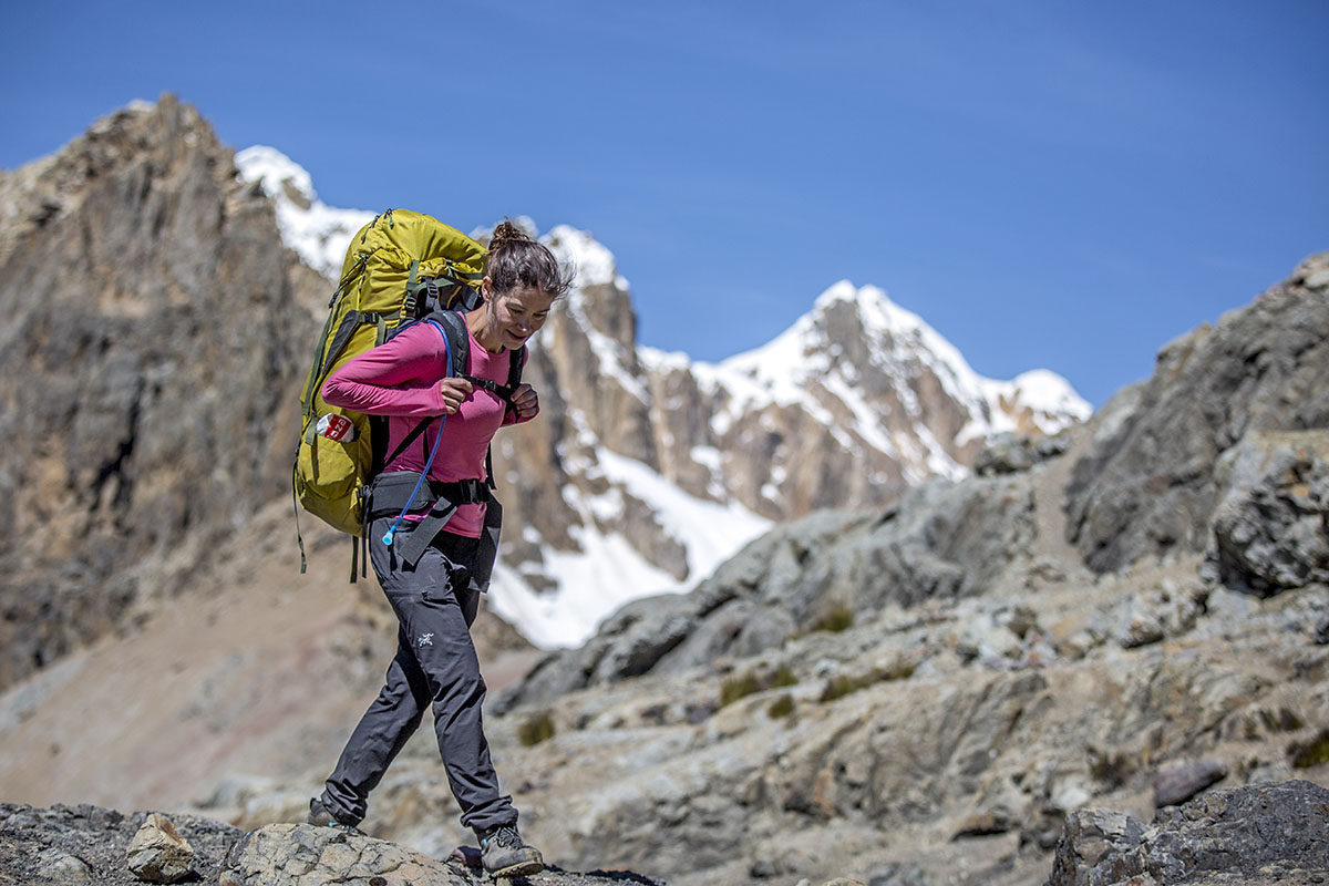 A woman in a pink baselayer backpacks in the mountains