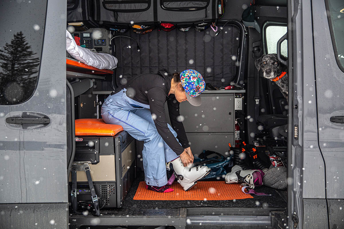 A woman inside a van puts on ski boots