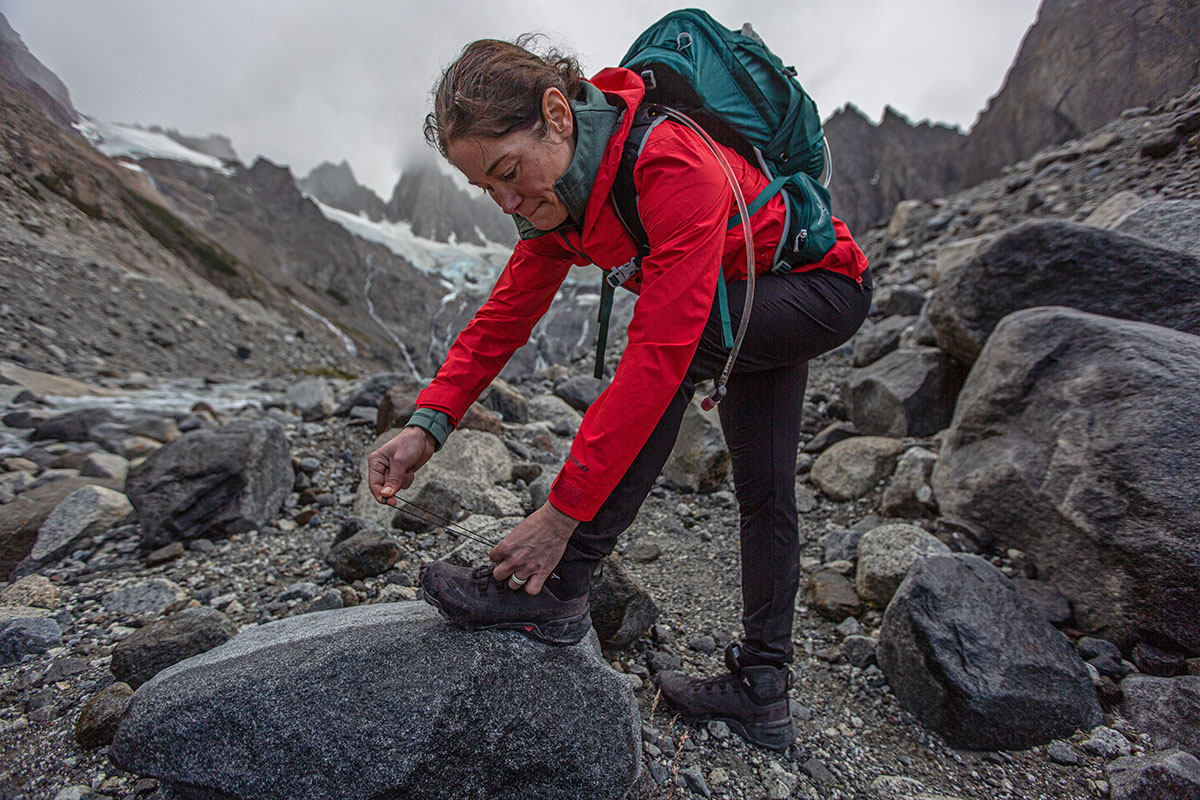 A backpacker laces her boots on a cold and overcast day in the backcountry.