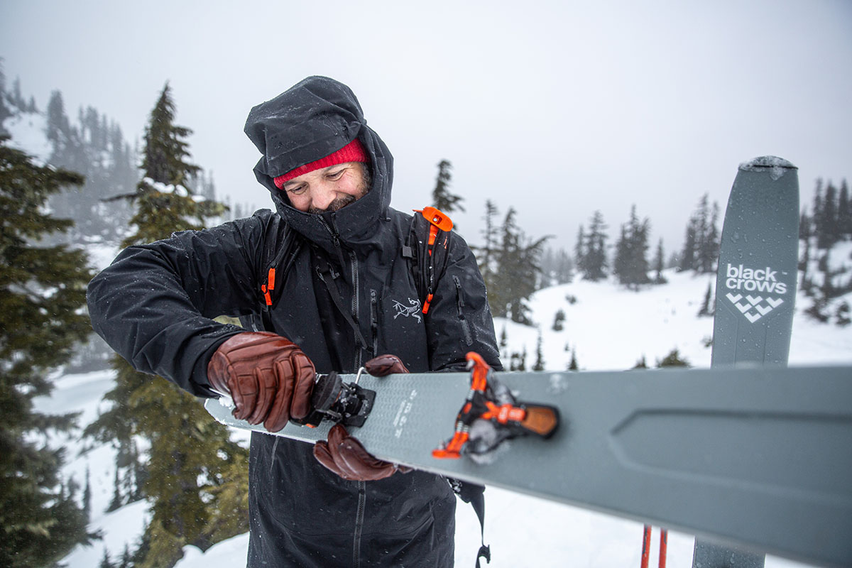 A man adjusting ski bindings with gloves on