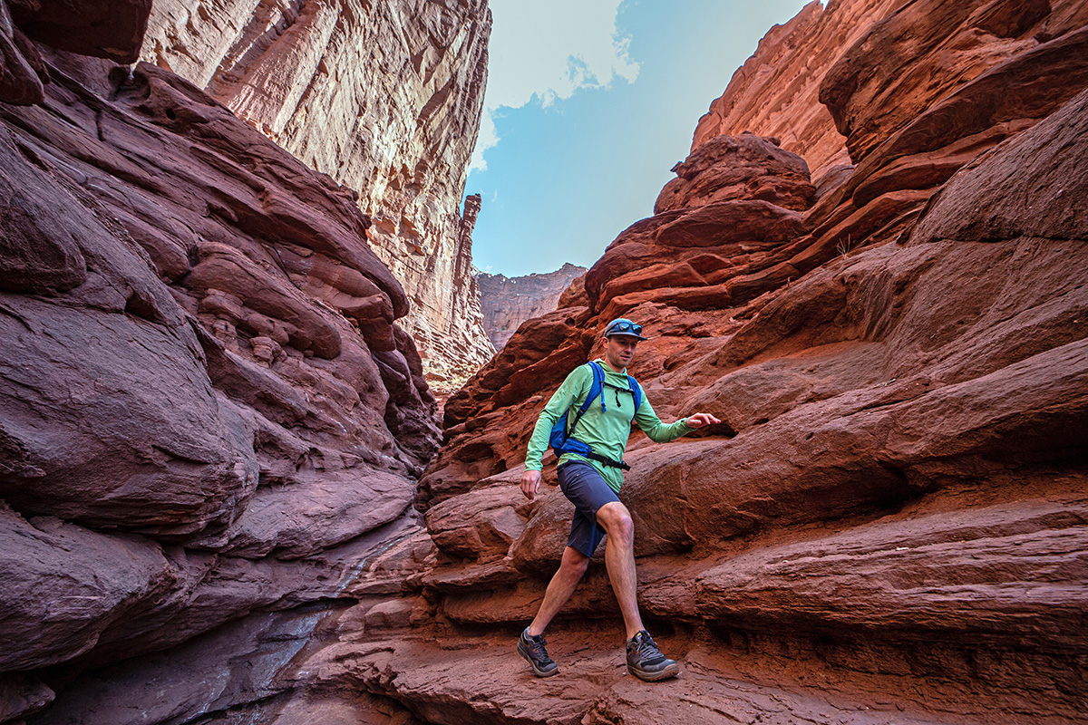 A man walks down a red rock canyon trail