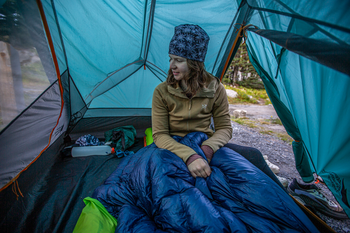 A woman sitting in a tent and wearing a brown fleece jacket