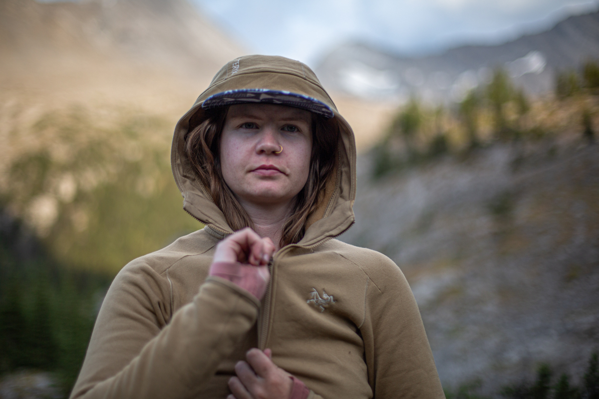 A woman zipping up the hood on a brown fleece jacket