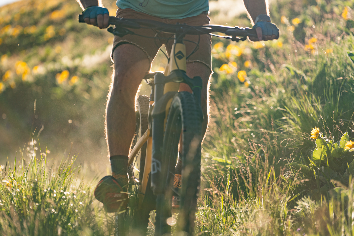A close up of someone riding a yellow mountain bike down a grassy hill