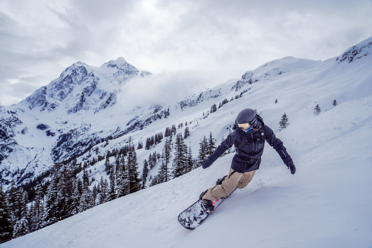 A woman snowboarding down a slope wearing snowboard pants