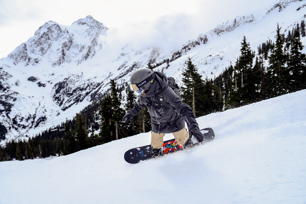 A woman leans forward as she snowboards down a slope at a resort
