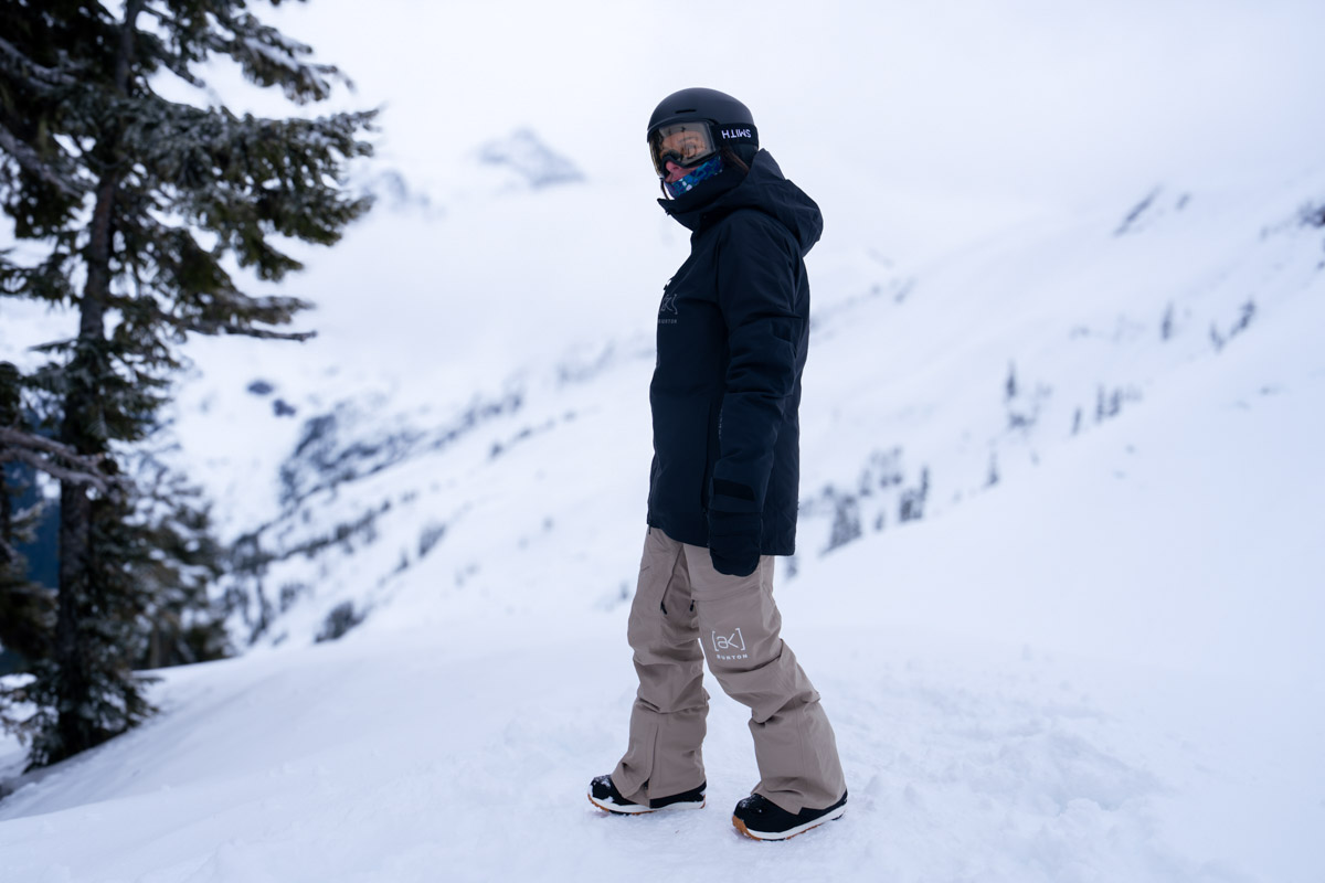 A woman standing at the ski resort wearing snowboard pants