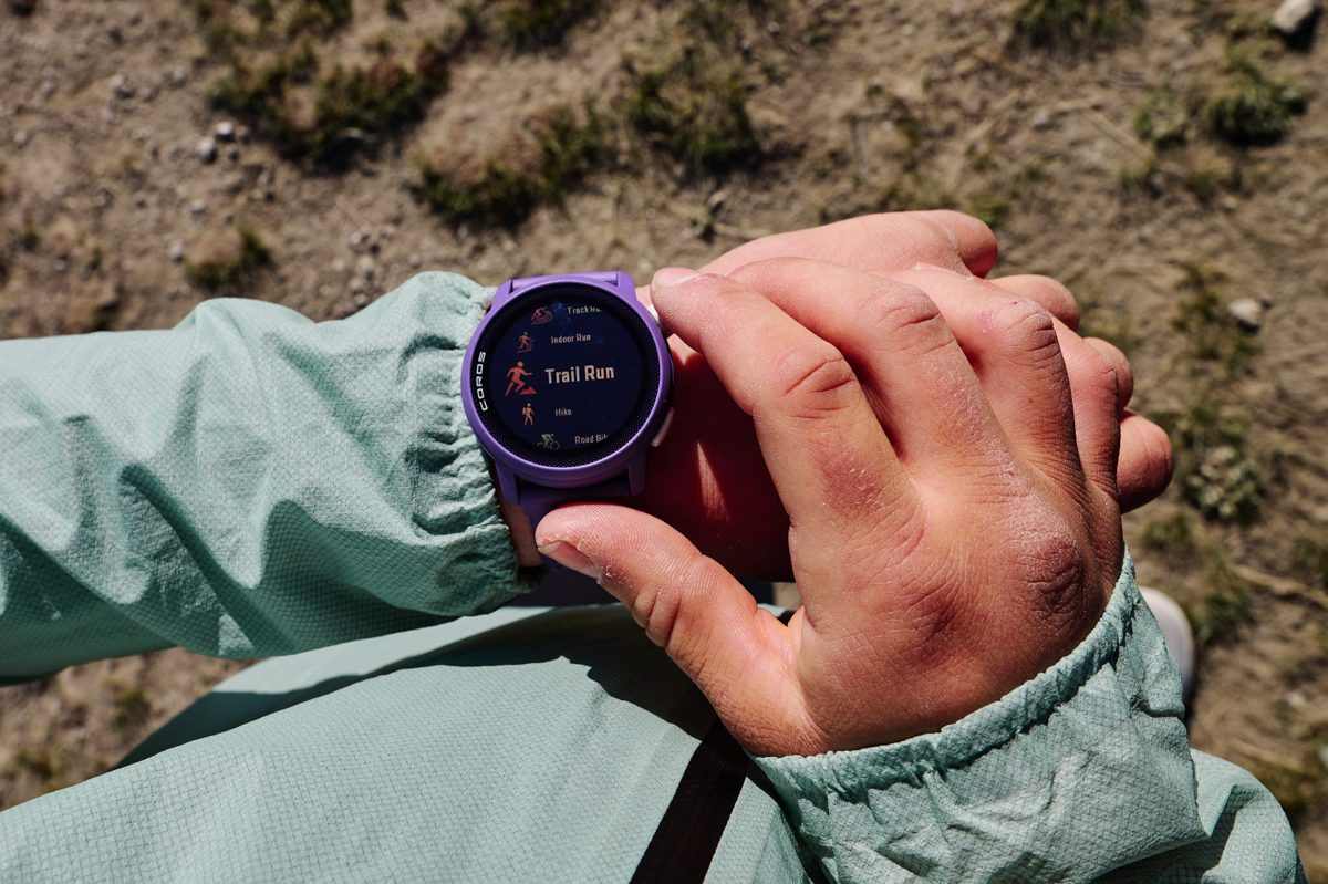 A close up of a purple GPS watch while a hand toggles through activity options