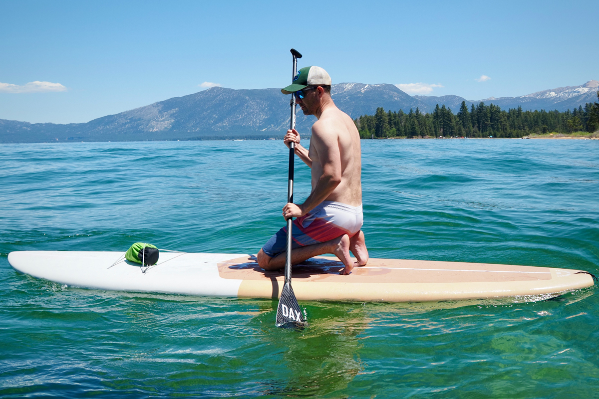A man kneeling on a paddle board on a lake