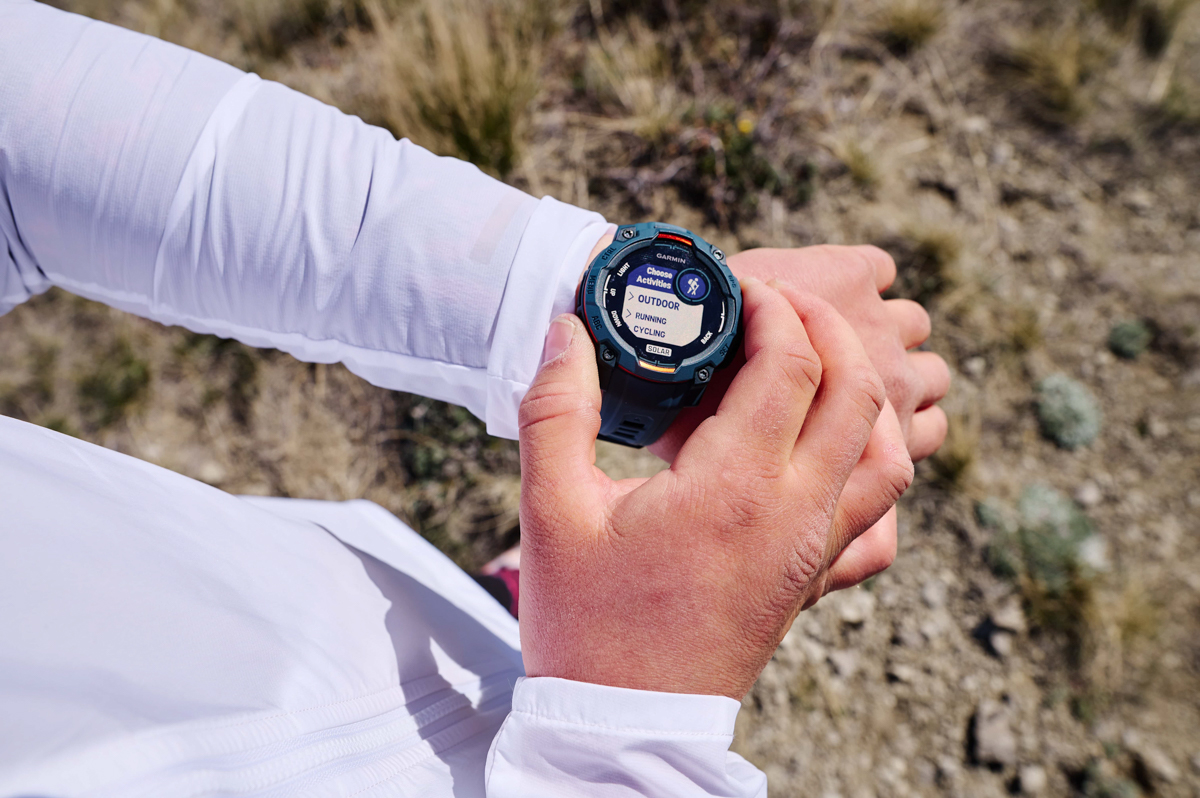 A close up of a hand using a blue GPS watch on the opposite wrist