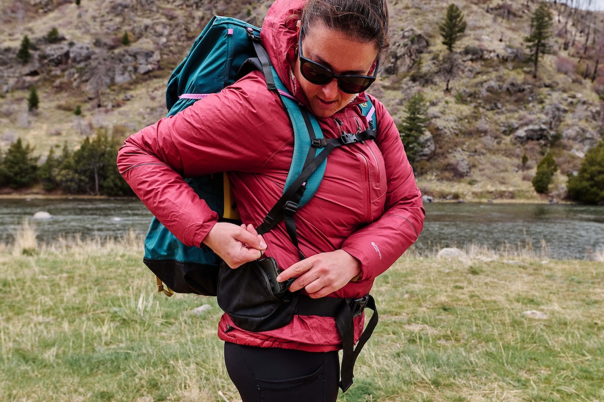 A woman is shown testing the pockets on the Gossamer Gear Mariposa by putting a phone in one of them