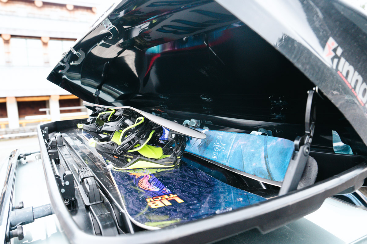 The inside of a rooftop cargo box full of both snowboards and skis