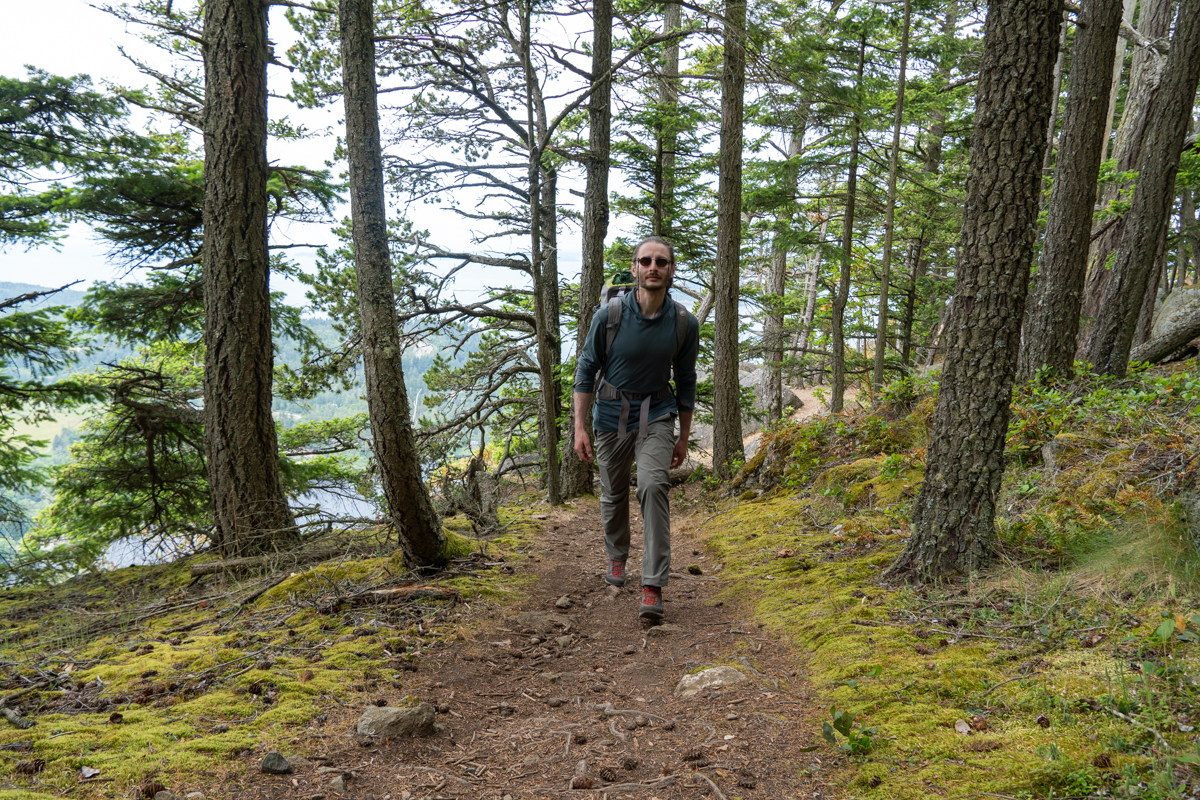 A man hiking on a steep forest trail wearing approach shoes
