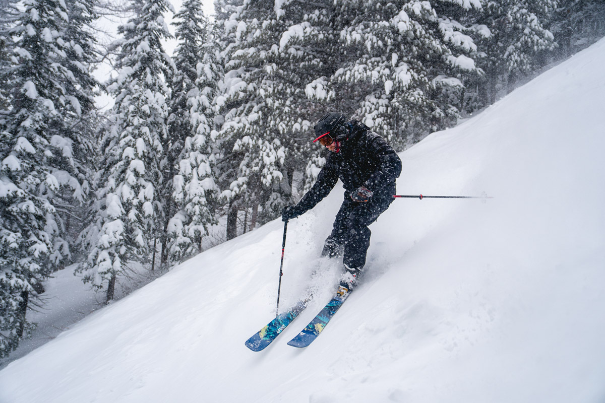 A man skiing down a steep snowy slope in ski boots