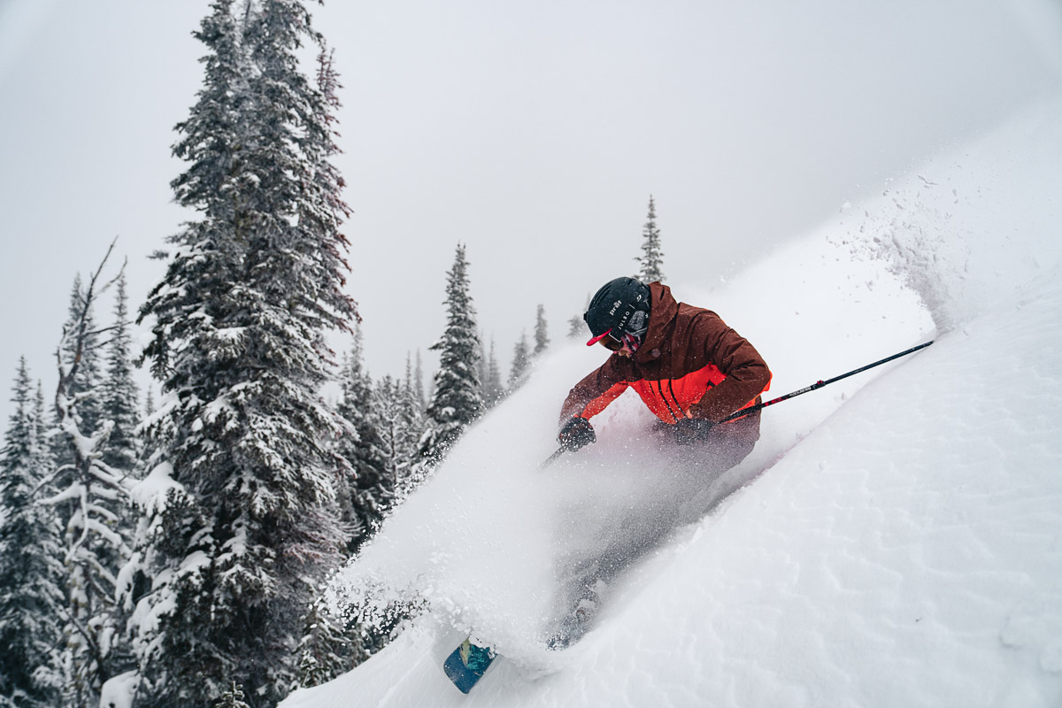 A man skiing quickly down a snowy hill in ski boots