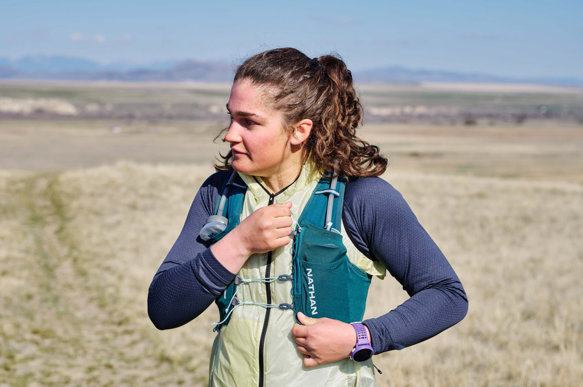 A close up of a woman wearing a baselayer and a running vest