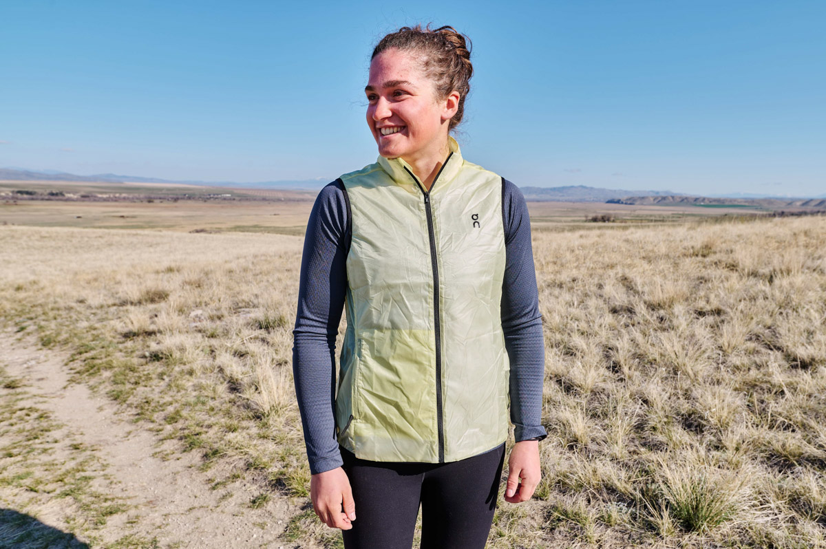 A woman smiles widely on a sunny trail