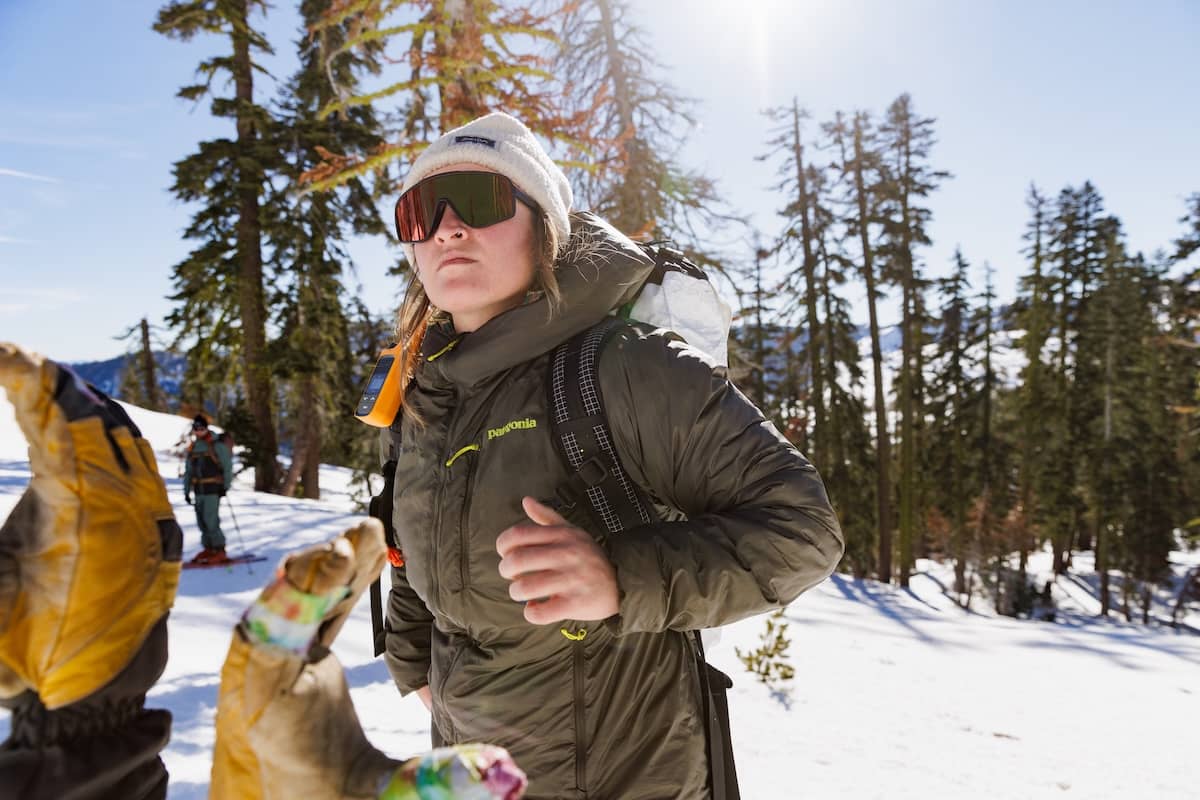 A woman looks off into the mountains wearing the Patagonia DAS Light Hoody