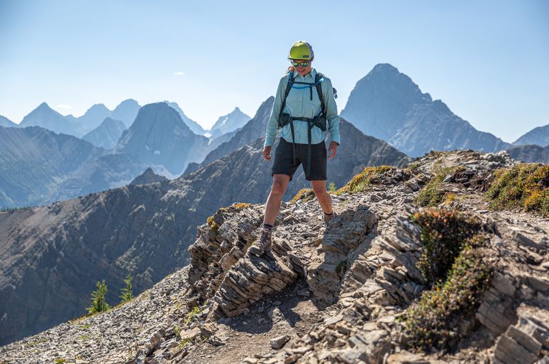 a woman walks on a ridgeline surrounded by mountains