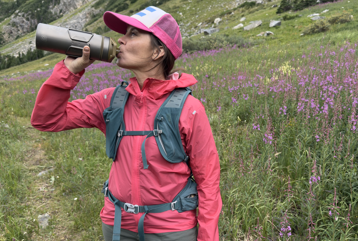 A woman drinking water from a bottle in a field of flowers