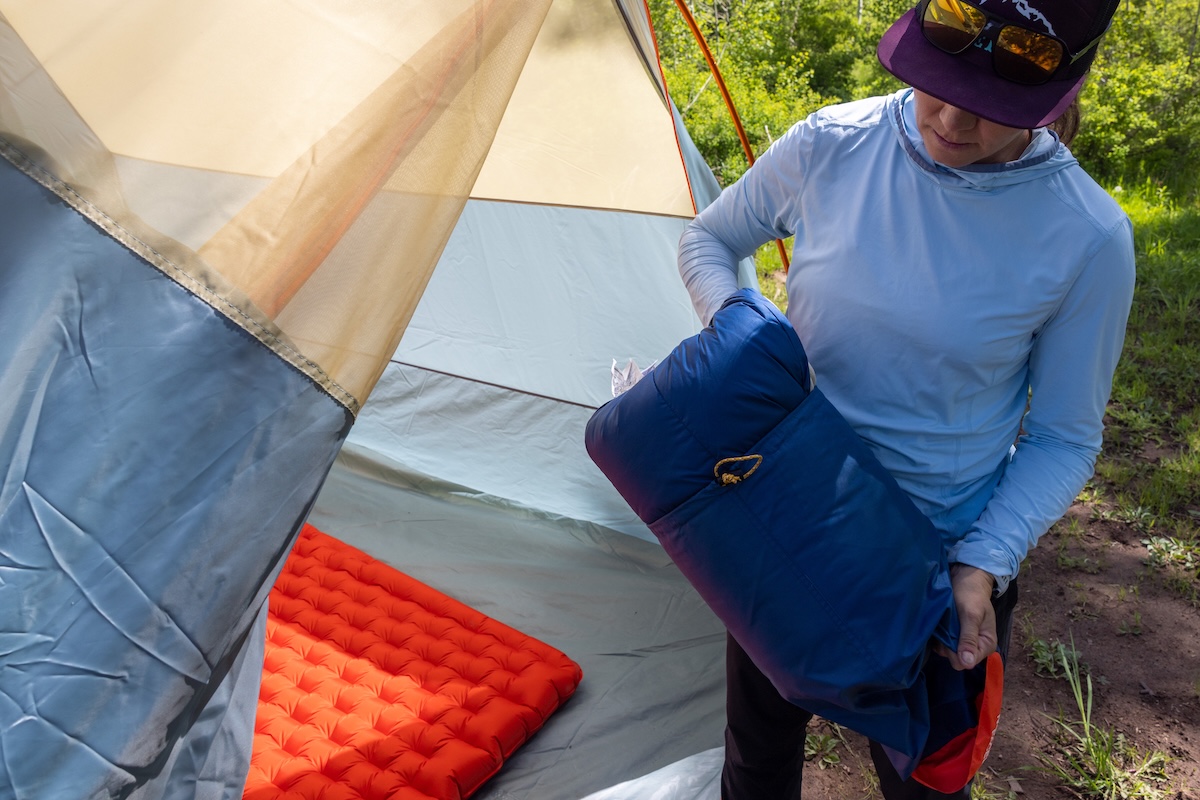 A women in the process of putting the Wawona Bed back into its stuff sack