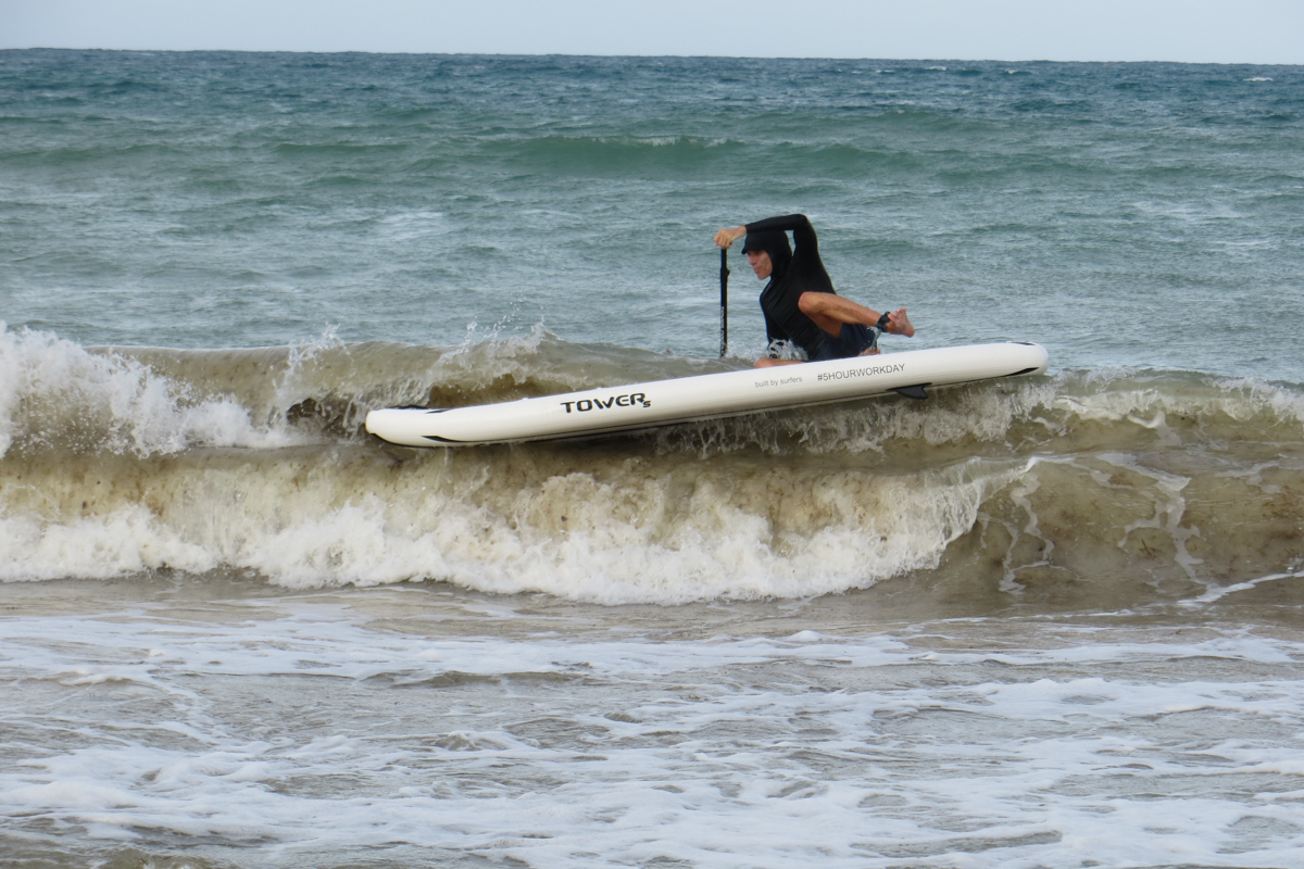 A man falling off a paddle board into an ocean wave