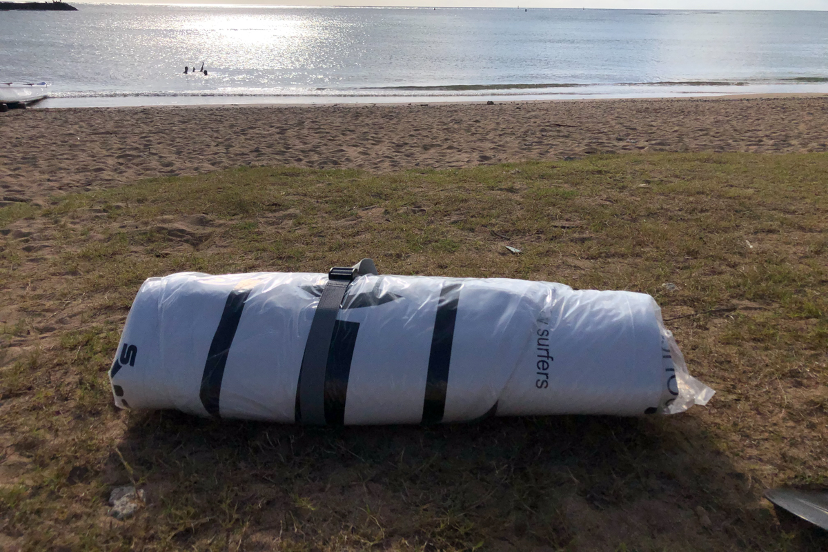 An inflatable paddle board rolled up on the beach