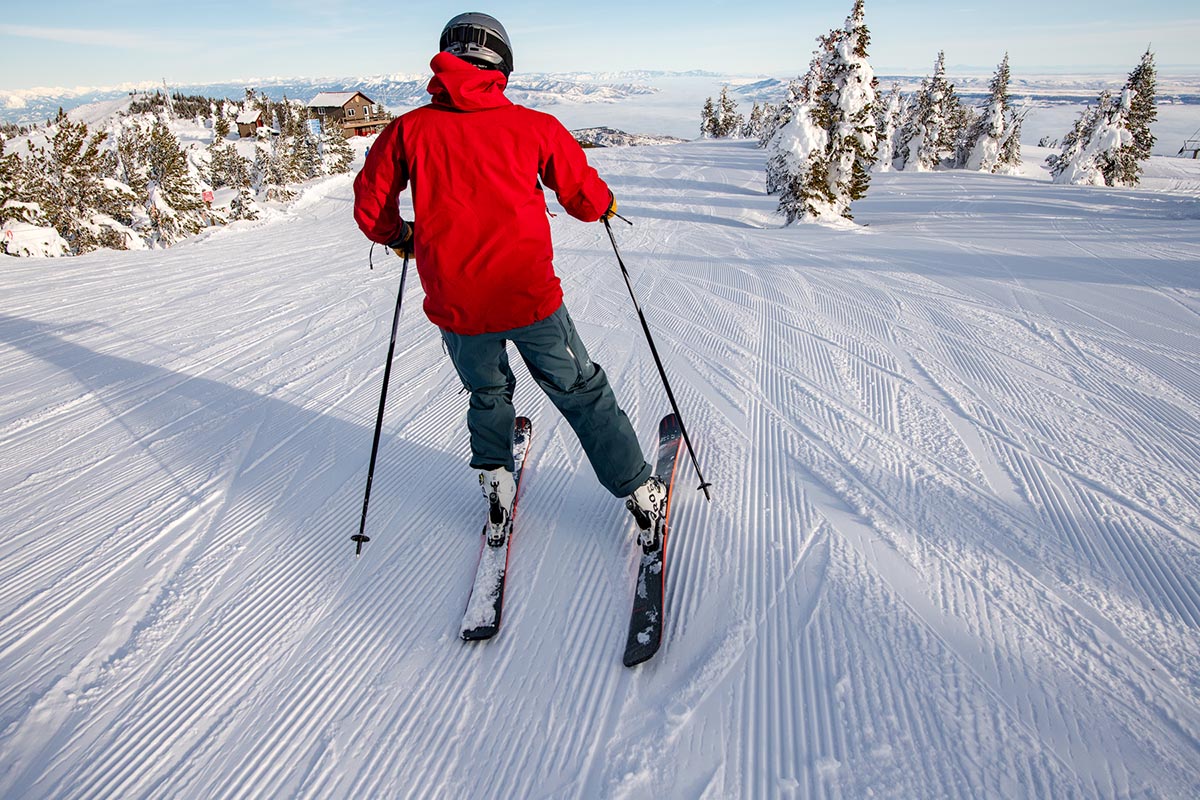 A skier glides down a groomed mountain path.