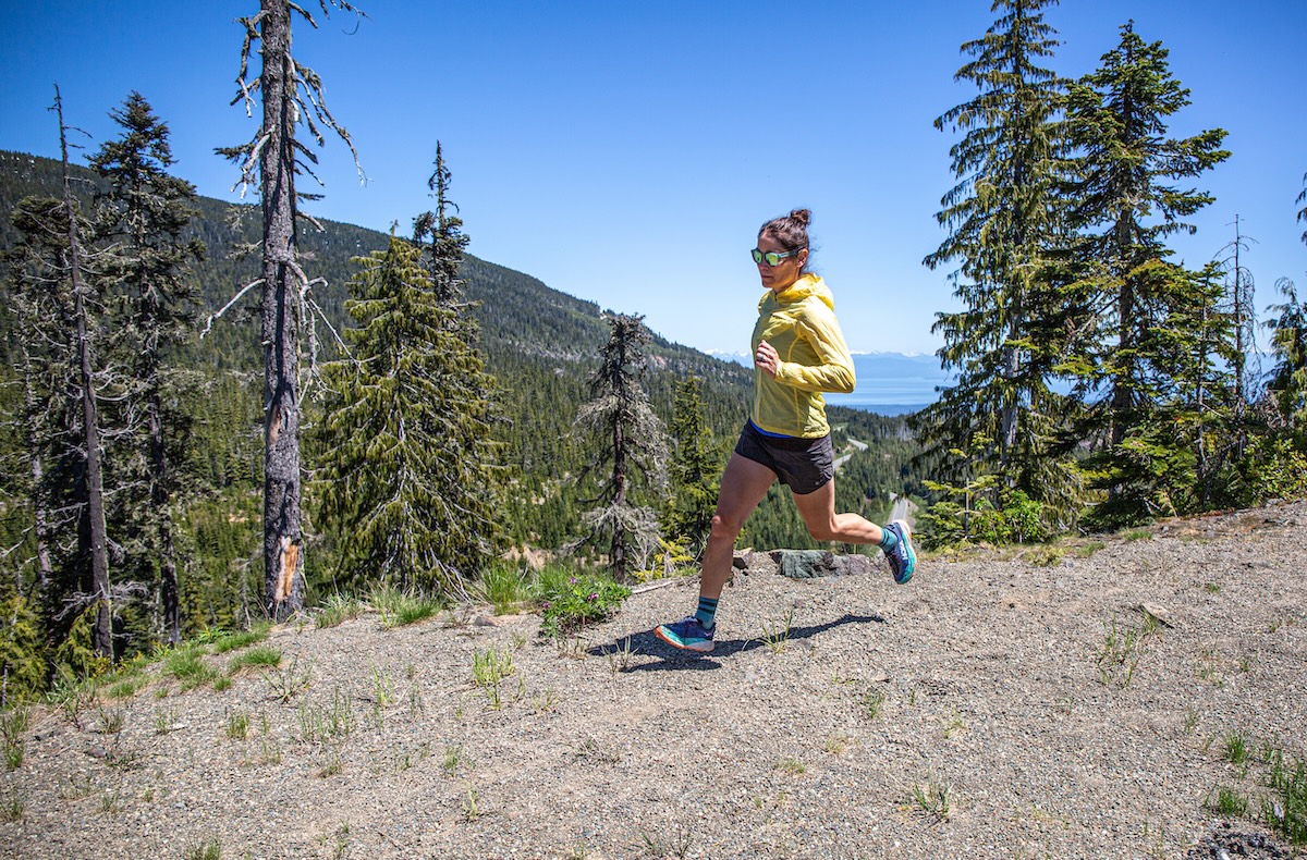 A woman running down a trail wearing the Hoka Speedgoat 6 shoe