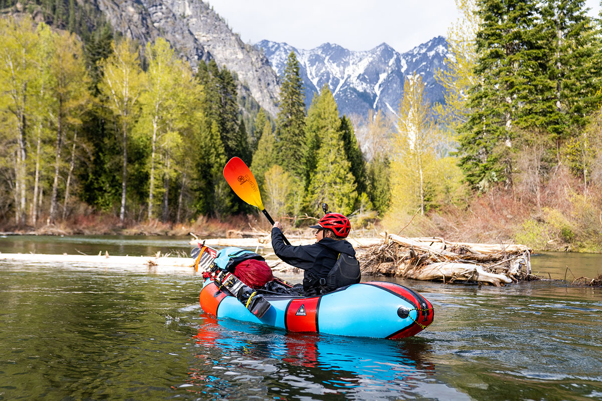 A woman paddles a packraft across a wilderness lake.