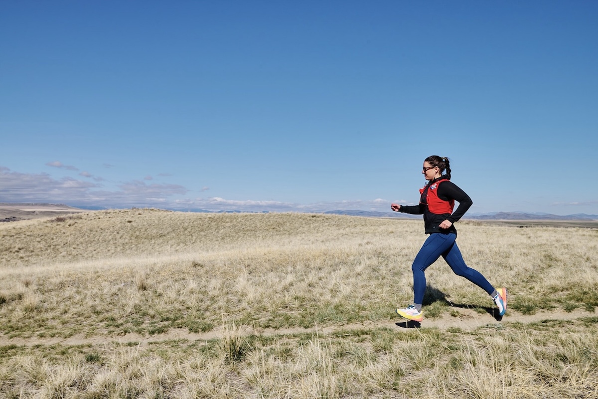 Running on a trail wearing the Salomon ADV Skin 5 running pack on a bluebird day