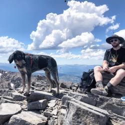 Ross sitting atop a mountain with his hound dog