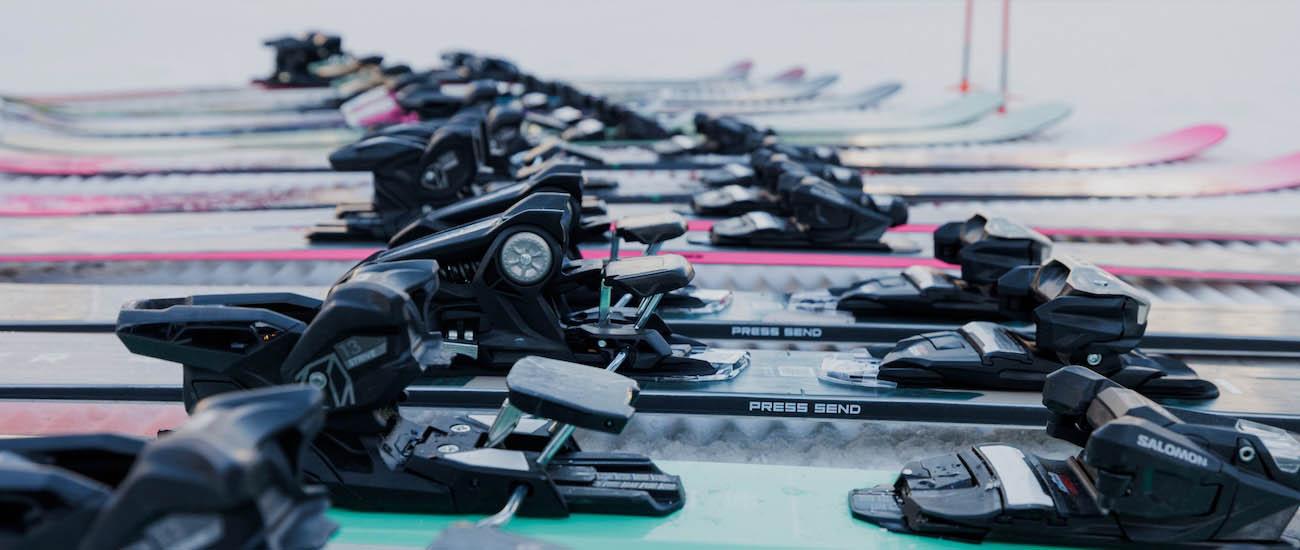 A close up of many ski bindings lined up on the snow