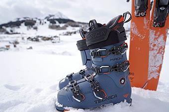 A pair of ski boots are placed next to a pair of skis. 